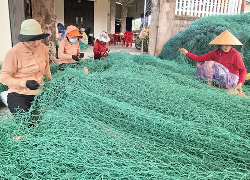Chị Mai Thị Ngọt (ngoài cùng bên trái) cùng nhóm thợ cần mẫn vá lưới thuê cho các chủ tàu cá - Ảnh: S.H
