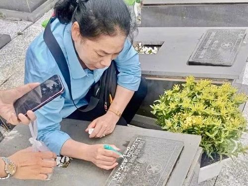 Thân nhân liệt sĩ Nguyễn Quốc Hội cẩn thận viết tên ông trên tấm bia mộ sau khi danh tính được xác định bằng giám định ADN.