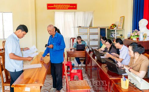 Trưởng Khóm 20 Huỳnh Quốc Tiếng (bìa trái) hỗ trợ người dân tra cứu thông tin liên quan đến các thủ tục hành chính.