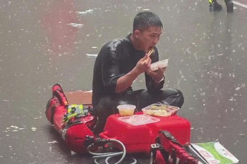 Lính cứu hỏa Trung Quốc ngồi ăn cơm giữa trời mưa.