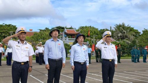 Các đại biểu hướng về cột mốc chủ quyền và lá cờ đỏ sao vàng tung bay trên nền trời xanh thẳm