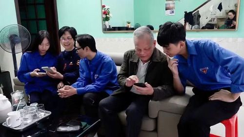 Đoàn viên, thanh niên phường Cẩm Phả hướng dẫn người dân cài đặt ứng dụng VNeID và sổ tay đảng viên điện tử.