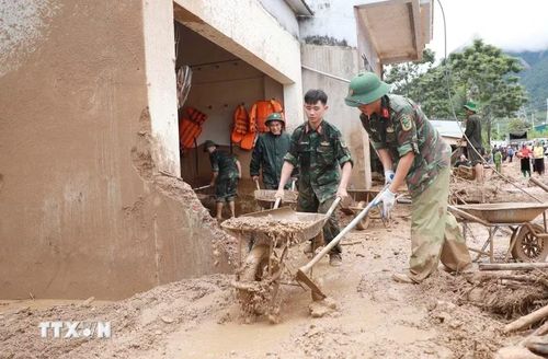 Lực lượng Quân đội giúp dân hót bùn đất, đá trôi vào nhà tại xã Mường Than. (Ảnh: Quý Trung/TTXVN)