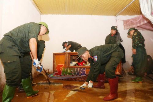 Hỗ trợ nhân dân dọn bùn đất trong nhà ở.