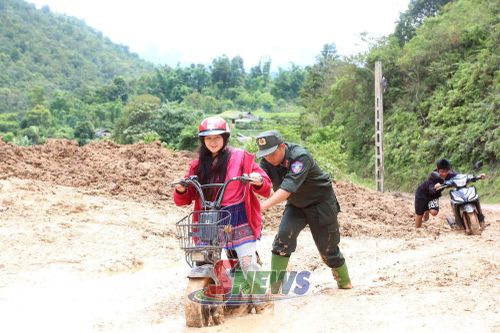 Cán bộ, chiến sĩ Cảnh sát cơ động hỗ trợ nhân dân đi qua vùng sạt lở.
