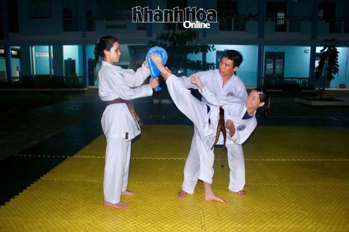 Huấn luyện viên hướng dẫn thực hiện kỹ thuật đá cao phối hợp với đích đá cầm tay tại lớp karatedo ở Trường Tiểu học Diên Lạc.