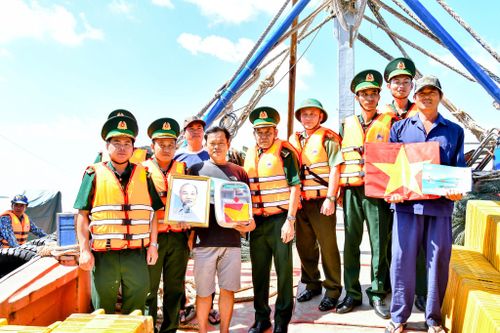 Lãnh đạo BĐBP và các đơn vị tham gia ra quân tuần tra, kiểm tra, kiểm soát trao tặng cờ Tổ quốc, ảnh Bác Hồ và tủ thuốc Biên phòng cho các chủ phương tiện khai thác đánh bắt thủy hải sản trên biển. Ảnh: Văn Long