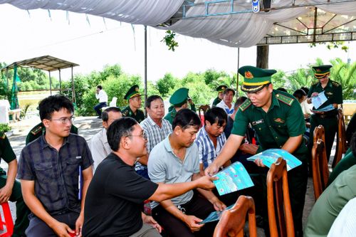 Cán bộ đồn Biên phòng Trung Bình cấp phát tờ rơi tuyên truyền chống khai thác IUU cho bà con ngư dân tham dự lễ ra quân. Ảnh: Văn Long