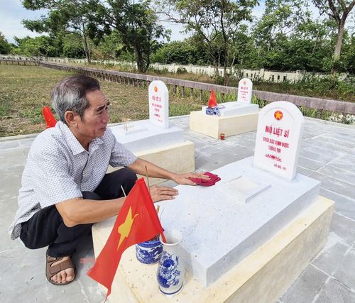 Ông Nguyễn Ngọc Tân cẩn mẫn lau chùi, chăm sóc chu đáo từng phần mộ liệt sĩ như người thân ruột thịt của mình - Ảnh: K.S
