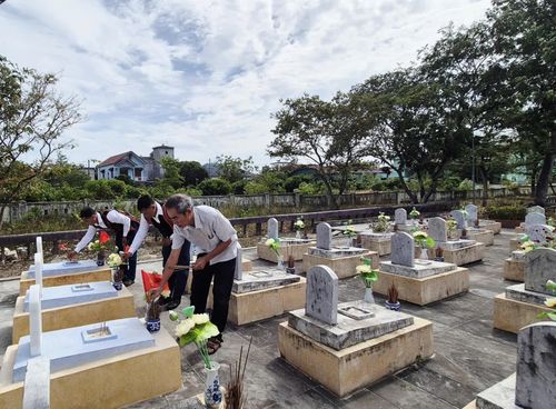 Ông Nguyễn Ngọc Tân (bên phải ngoài cùng) và anh Hồ Văn Phương (bên trái ngoài cùng) thắp hương tại các phần mộ liệt sĩ vừa được quy tập về nghĩa trang - Ảnh: K.S