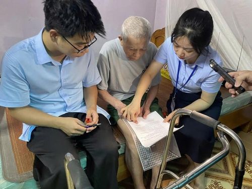 Công chức Chi nhánh Trung tâm phục vụ hành chính công số 6 hỗ trợ cụ ông Nguyễn Văn Tấc 91 tuổi tại xã Phù Đổng chứng thực chữ ký tại nhà. Ảnh: NT