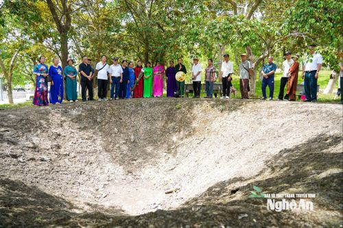 Du khách nghe thuyết minh bên hố bom lịch sử tại Khu Di tích quốc gia đặc biệt Truông Bồn.