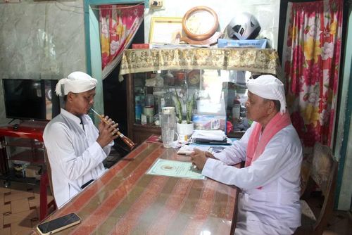 Anh Thông Minh Tranh đang được ông Thông Long truyền dạy kỹ thuật chơi kèn Saranai. (Nguồn: Vietnam+)