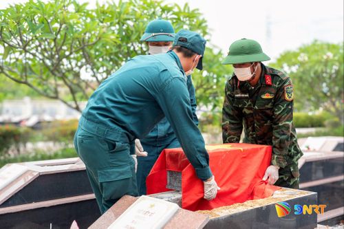 Nghi thức phủ cờ Tổ quốc lên quách hài cốt liệt sĩ để đưa đến khu vực lấy mẫu được thực hiện nghiêm trang. Ảnh: HOÀNG ĐẠO