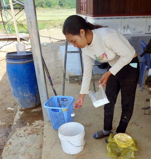 Người dân pha Cloramin B lau khử khuẩn môi trường, đồ chơi, vật dụng sinh hoạt để phòng bệnh TCM tại xã Tà Năng