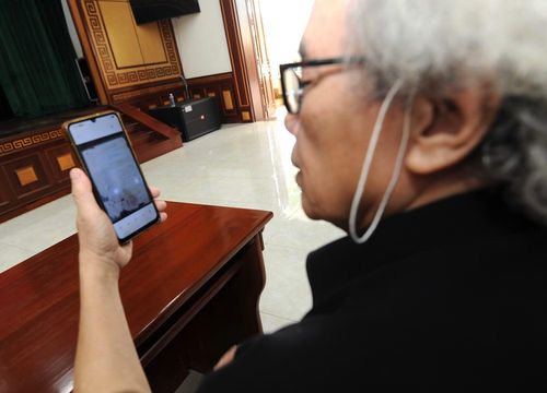 Cụ Phan Đức Nhuận đọc thông tin về em trai, liệt sĩ Phan Đức Thắng với hy vọng tìm lại được tro cốt của em qua chiến dịch thu nhận mẫu ADN.