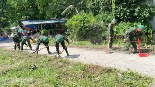 Bộ đội tham gia phát quang cỏ xâm chiếm mặt lộ giao thông.