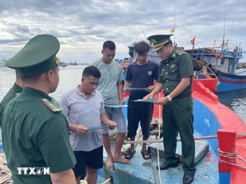 Thiếu tá Mai Văn Tuấn, Chính trị viên phó Đồn Biên phòng Lý Sơn (bên phải) trao đổi với chủ tàu và các thuyền viên về chống khai thác thủy sản bất hợp pháp trước mỗi chuyến tàu ra khơi. (Ảnh: Kha Phạm/TTXVN)