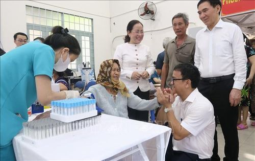 Ông Huỳnh Minh Chín (ngồi, bên phải), Phó Giám đốc Sở Y tế Thành phố Hồ Chí Minh, động viên một người cao tuổi tại phường Bình Qưới trong khi lấy máu xét nghiệm.
