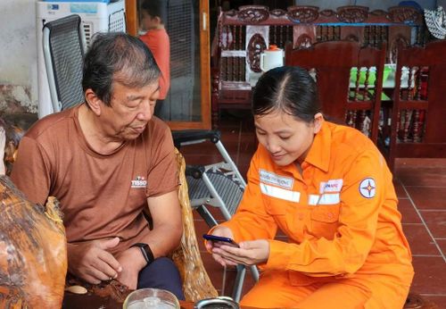 Nhân viên điện lực giới thiệu ứng dụng EVN CSKH tới khách hàng. Ảnh: Khánh Ly/Bnews/Vnanet.vn