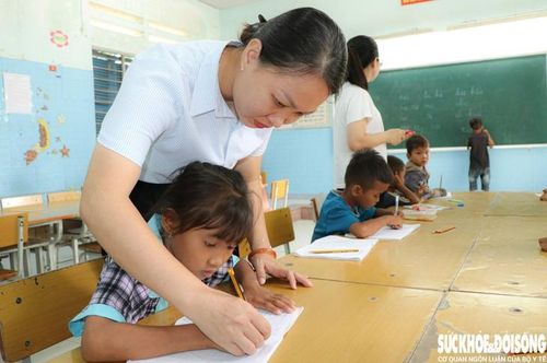 Cô giáo Võ Nguyên Thục Vân nhẹ nhàng cầm tay học trò nắn từng nét chữ. Ảnh: Duy Ngọc.