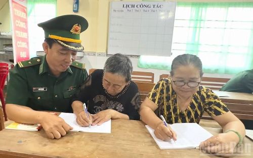 Thiếu tá Bùi Văn Hào hướng dẫn bà Trần Thị Sen viết chữ.