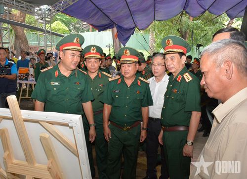 Đại tướng Phan Văn Giang xem các hình ảnh về quá trình tìm kiếm, quy tập hài cốt liệt sĩ tại Công viên Lê Thị Riêng. 