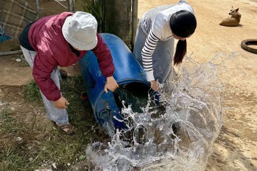 Người dân xử lý thùng nước chứa lăng quăng để phòng bệnh sốt xuất huyết tại xã Quảng Khê