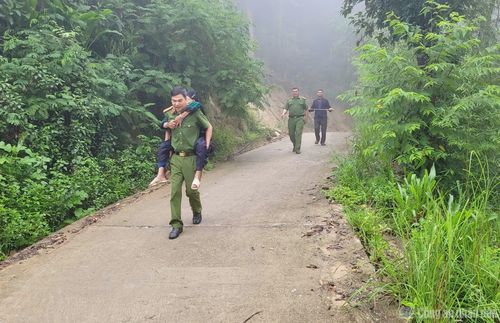 Cán bộ Công an xã Bản Máy cõng thân nhân liệt sĩ Sin Diu Mìn đến Trạm Y tế để lấy mẫu ADN.