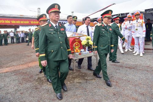 Các đại biểu thực hiện nghi thức di chuyển hài cốt liệt sĩ về nhà quàn để dâng hương. (Ảnh: Lương Ý)