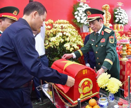 Đại tướng Phan Văn Giang cùng Bí thư Thành ủy Đồng Nai Vũ Hồng Văn phủ cờ Tổ quốc lên hài cốt liệt sĩ được tìm thấy tại xã Minh Đức. (Ảnh: Lương Ý)