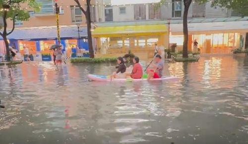 Người dân trèo thuyền ván di chuyển trên đường phố ngập nước ở Thượng Hải, ngày 19/7. (Ảnh: HK01)