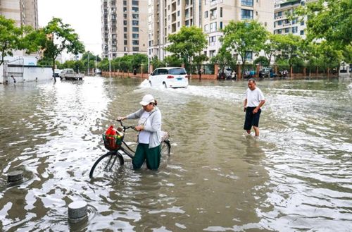 Người dân di chuyển trên đường phố ngập nước ở thành phố Thượng Hải. (Ảnh: SCMP)