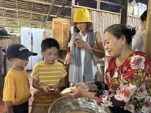 Một bé trai nước ngoài trải nghiệm làm bánh lá mít.