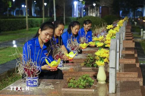 Đoàn viên thanh niên thắp đèn hoa sen, dâng hương tại phần mộ các Anh hùng liệt sỹ ở Nghĩa trang Liệt sỹ quốc gia A1 (Điện Biên). (Ảnh: Xuân Tư/TTXVN)