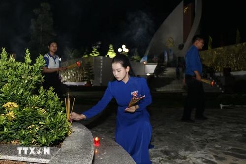 Đoàn viên thắp hương lên phần mộ liệt sỹ. (Ảnh: Hồng Thái/TTXVN)