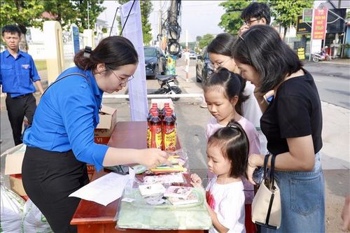 Các em nhỏ ở thành phố Đồng Nai được người lớn hướng dẫn đem rác đổi quà để bảo vệ môi trường.