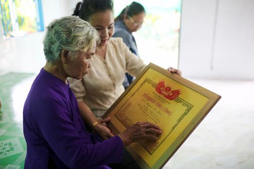  Bà Lệ nâng niu tấm bằng Tổ quốc ghi công của liệt sĩ Huỳnh Văn Quên. Bà từng lưu giữ những lá thư người thương gửi về từ chiến trường, nhưng sau một mùa mưa bão, tất cả đã không còn nguyên vẹn. Ảnh: Quỳnh Danh. 