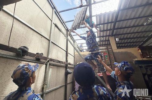 Cán bộ, chiến sĩ Lữ đoàn 175 cùng các lực lượng đưa những tấm lợp bị hư hỏng xuống khỏi mái nhà.