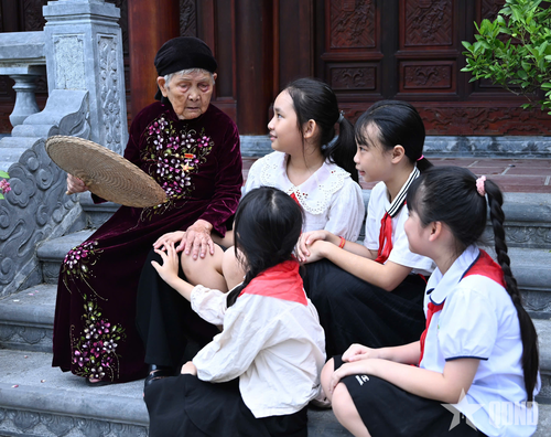  Các em học sinh chăm chú lắng nghe Bà mẹ Việt Nam anh hùng Phan Thị Mùi kể chuyện về những năm tháng chiến tranh. Đạo lý “Uống nước nhớ nguồn” được trao truyền từ thế hệ đi trước đến thế hệ hôm nay. 