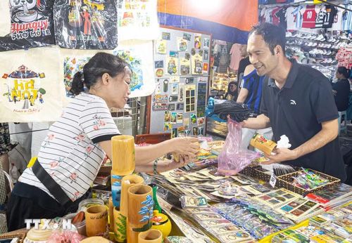 Nụ cười rạng rỡ của du khách quốc tế khi lựa chọn các sản phẩm quà lưu niệm thủ công mang đậm dấu ấn Hà Nội tại chợ đêm phố cổ. Sự thân thiện của tiểu thương cùng các mặt hàng quà tặng phong phú, mang bản sắc bản địa không chỉ giúp thúc đẩy tiêu dùng du lịch mà còn góp phần lan tỏa văn hóa Việt Nam ra thế giới. (Ảnh: Tiến Long/TTXVN phát)