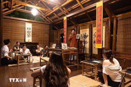 Du khách trong và ngoài nước trải nghiệm lớp học thư pháp cùng thầy đồ tại không gian nhà thầy đồ thuộc tour trải nghiệm đêm “Tinh hoa đạo học” - Văn Miếu-Quốc Tử Giám. Việc đưa các hoạt động tương tác văn hóa dân gian vào chương trình du lịch ban đêm giúp đa dạng hóa sản phẩm, gia tăng trải nghiệm thực tế và quảng bá giá trị di sản Thủ đô tới khách du lịch. (Ảnh: Tiến Long/TTXVN phát)