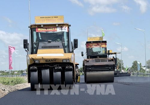 Xe thảm nhựa và các phương tiện thi công hoạt động liên tục trên đường dẫn vào tuyến cao tốc Châu Đốc - Cần Thơ - Sóc Trăng đoạn qua phường Vĩnh Tế, An Giang. Ảnh: Thanh Sang - TTXVN