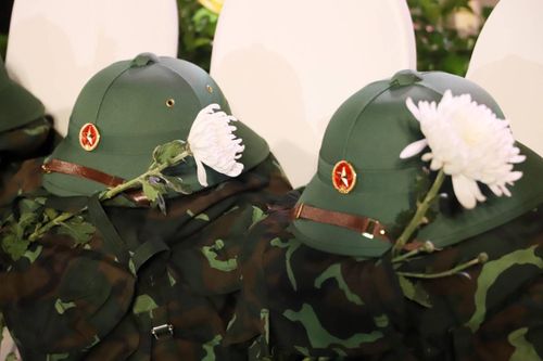 Những chiếc ba lô, mũ cối và một bông hoa cúc trắng tưởng nhớ đến các liệt sĩ được đặt trang trọng ở hàng ghế đầu. 