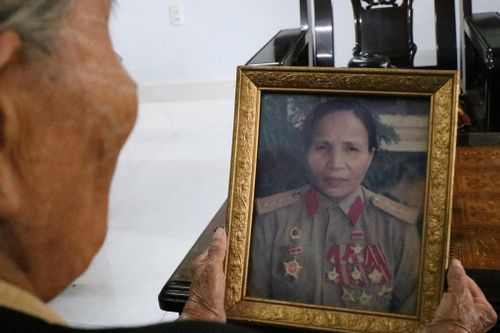 Bên tấm chân dung ngập huy chương, Anh hùng Lực lượng Đặng Thị Én kể lại những năm tháng chiến đấu kiên cường cùng những mất mát không gì bù đắp được của gia đình trong chiến tranh. Ảnh: THÚY HIỀN