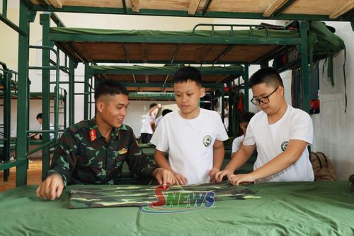 Các "chiến sĩ nhí" thực hành gấp chăn màn dưới sự hướng dẫn của cán bộ huấn luyện.