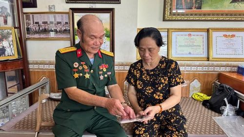 Thương binh Lê Long Triệu cùng vợ xem lại những bức ảnh, kỷ vật lưu giữ ký ức về một thời chiến đấu và hành trình tìm kiếm đồng đội. Ảnh: Tiến Sinh