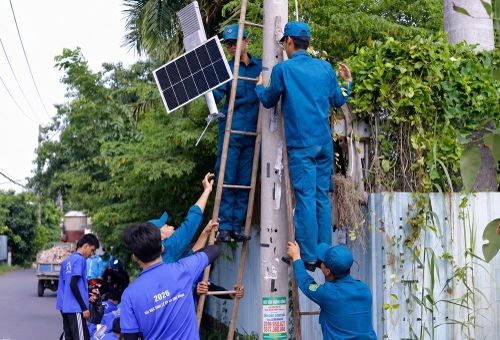 Sinh viên tình nguyện Đại học Kinh tế TP Hồ Chí Minh cùng chiến sĩ dân quân tự vệ thực hiện Chương trình “Thắp sáng đường quê”. 