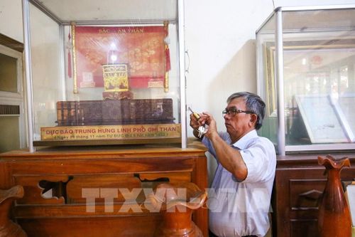 Ông Huỳnh Văn Mộc, Phó Trưởng Ban Quản lý Khu di tích Lăng mộ Quan lớn Trà Vong kiểm tra, bảo quản các hiện vật và sắc phong được lưu giữ tại di tích. Ảnh: Giang Phương – TTXVN