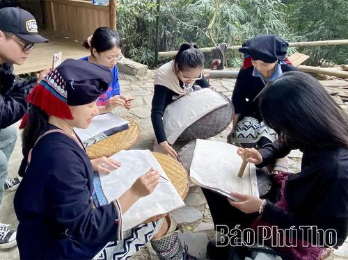 Du khách trải nghiệm hoạt động vẽ sáp ong tại điểm du lịch cộng đồng đậm bản sắc văn hoá người Dao Tiền ở thôn Sưng Bai.